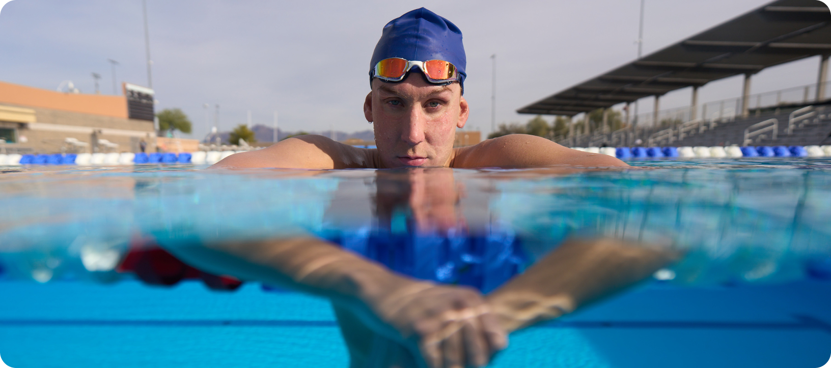 Chase Kalisz in a swimming pool, facing forward, with his head above the water line and his hands below